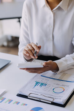 Woman accountant use calculator and computer with holding pen on