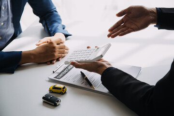 A car rental company employee is handing out the car keys to the renter after discussing the rental details and conditions together with the renter signing a car rental agreement. Concept car rental.