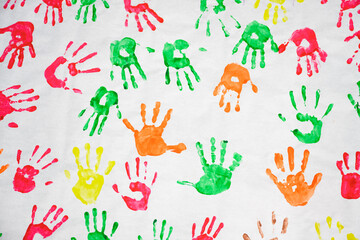 Colorful kids hand prints on white paper made with red, green, orange and yellow paint