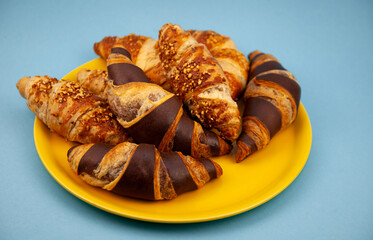 Chocolate croissants or croissant with nut crumbs on a plate. Delicious breakfast on the table. Tasty sweet baking dessert for coffee. Food background. Fresh buttery croissants rolls