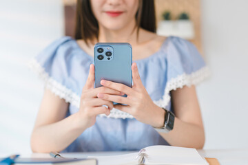 In a cozy living room at home, a beautiful young woman engrossed in messaging on her smartphone...