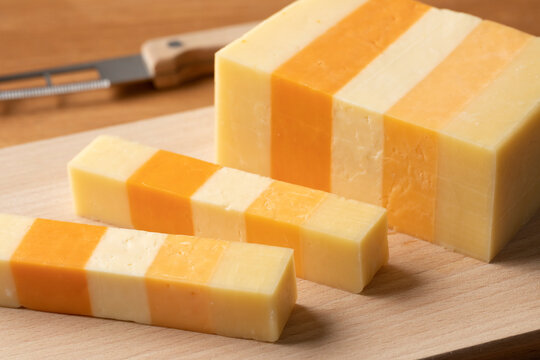 Piece of English Classic Five, variation of Cheddar cheese, on a cutting board for a snack close up 