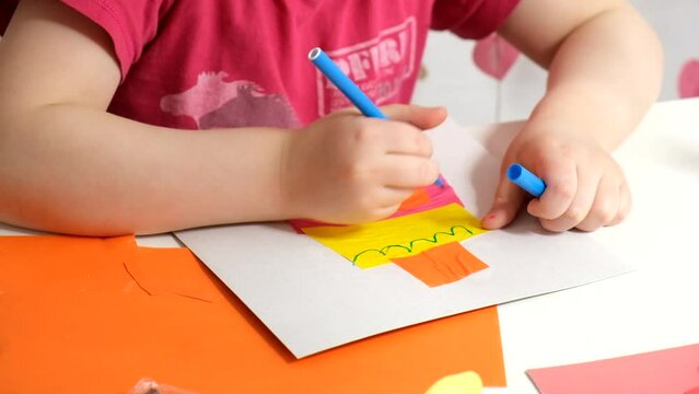 a girl makes an application from colored paper, a postcard with her own hands