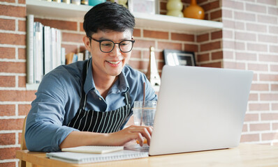 Fototapeta premium close up young business owner man use laptop to check order or feedback from customer or planning about marketing in home office for startup lifestyle concept