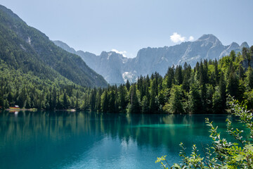 Fototapeta na wymiar View of Lago Inferiore die Fusine in the Julian Alps of northeastern Italy with the dramatic rock face of Mount Mangart in the background