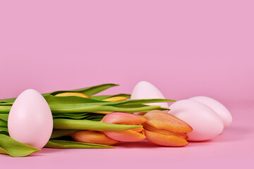 Obraz na płótnie Canvas Tulip spring flowers and pink Easter eggs on pink background with copy space