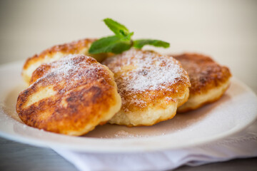 Sweet cooked cheesecakes in powdered sugar in a plate