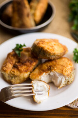 A piece of hake fish fried in a crispy crust, in a plate.