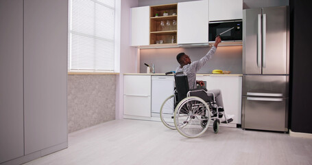 Disabled Man Using Grabber Tool To Control Microwave