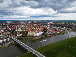 Obraz premium torgau with a cloudy sky. rain clouds over the city. river elbe and elbe bridge in the foreground. old town and surroundings in the background