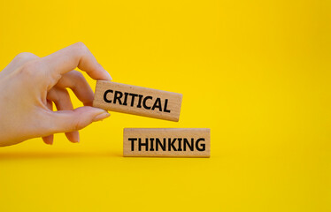 Critical thinking symbol. Wooden blocks with words Critical thinking. Businessman hand. Beautiful yellow background. Business and Critical thinking concept. Copy space.