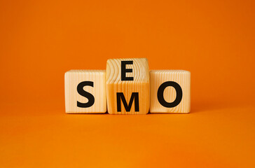 SEO vs SMO symbol. Turned wooden cubes with words SMO to SEO. Beautiful orange background. SEO vs SMO and business concept. Copy space