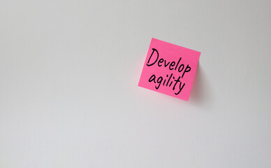 Develop agility symbol. Pink steaky note with concept words Develop Agility. Beautiful white background. Business and Develop agility concept. Copy space