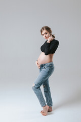 Young pregnant girl in jeans on a white background