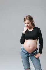 Young pregnant girl in jeans on a white background