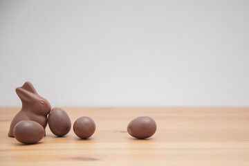 Chocolate bunny and chocolate eggs on a wooden table. Easter background.