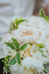 The wedding bouquet of the bride with wedding rings during the wedding walk of the bride and groom