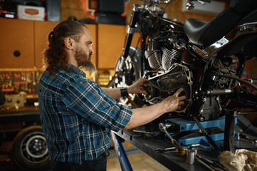 Fototapeta na wymiar Man mechanic fixing motorcycle engine working at garage workshop