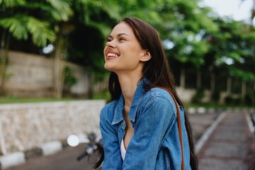 Portrait of a woman brunette smile with teeth walking outside against a backdrop of palm trees in the tropics, summer vacations and outdoor recreation, the carefree lifestyle of a freelance student.