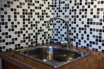 Clean sink with pouring water in the kitchen, metal faucet and sink in an old home interior.