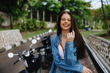 Portrait of a woman brunette smile with teeth walking outside against a backdrop of palm trees in the tropics, summer vacations and outdoor recreation, the carefree lifestyle of a freelance student.