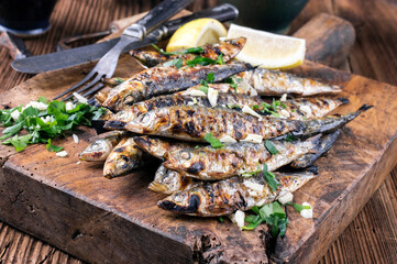 Traditional Italian barbecue anchovies with herb es lemon slices served as close-up on an old...