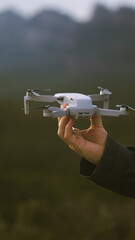 A person's hand flying a drone with its remote control