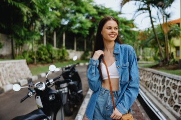 Portrait of a woman brunette smile with teeth walking outside against a backdrop of palm trees in the tropics, summer vacations and outdoor recreation, the carefree lifestyle of a freelance student.