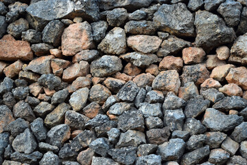 Irregularly shaped stacked rocks form the texture of an old wall or construction