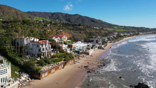 2023 - Excellent aerial footage of ocean waves hitting the rocky shore outside beach houses at Point Mugu, California.