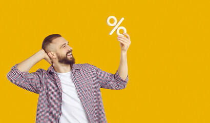 Business, finance, mortgage rates, or discounts. Happy man holding wooden percent sign in his hand...