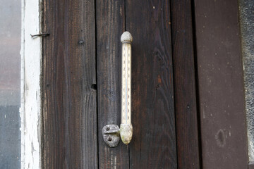 Outdoor thermometer attached to the wall of a wooden hut.