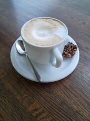 Cup with coffee on a wooden surface. White cup on a saucer with a spoon