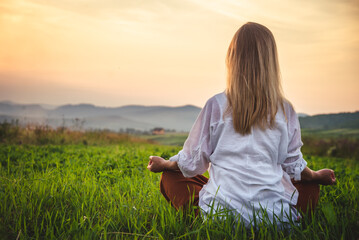 Woman doing yoga on the green grass at the mountain. Carpathians