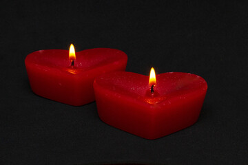  two red candles in the form of hearts on a black background (valentine's day)