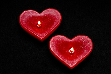 top view of two red candles in the form of hearts on a black background (valentine's day)