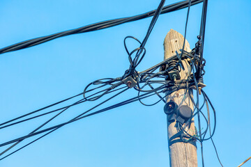 Electrical cables and wires in disarray on wooden pole in Spain