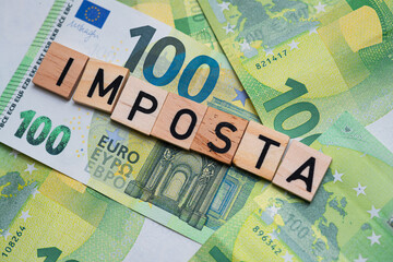 inscription Imposta which means tax in Italian next to euro banknotes. Concept showing the Italian economy