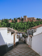 Fototapeta na wymiar The Alhambra Palace seen from the tiny streets with white houses in Albacin, Granada, Andalucia, Spain