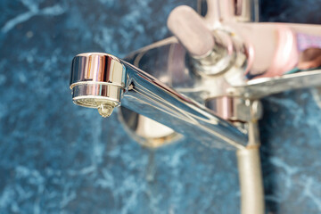 Obraz premium A drop of water drips from a leaky faucet