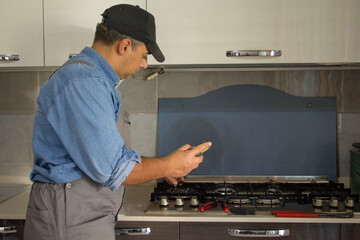 Image of a handyman technician who with a detector carries out checks in a kitchen for safety and gas leaks from the stove. Prevention and safety at home.
