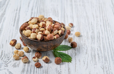 Hazelnuts raw and peeled in a wooden cup on a white wooden background. Rustic style. The concept of vegetarian and diet snacks.