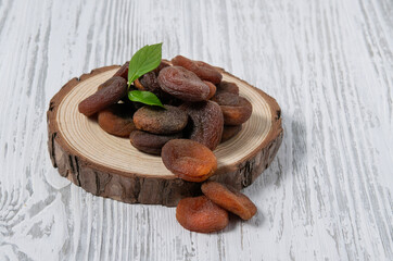 Dry fruits apricot  in a wooden board  on a white wooden background. Rustic style. The concept of vegetarian and diet snacks.