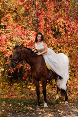 Bride in white dress near a horse in the autumn forest