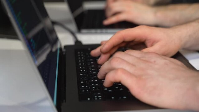 The hands of two people typing on the laptop keyboard