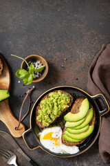 Wholemeal bread toast sliced avocado and poached egg on a stone background. Healthy breakfast concept, sandwich with avocado and egg. View from above. Copy space.