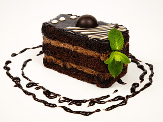 Pieces of chocolate cake with chocolate cream lying on a white plate, decorated with chocolate sauce  
