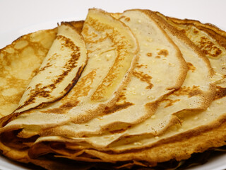 Pancake-crepes stacked on a plate in a pile, background