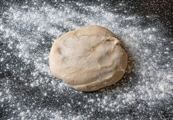 Dough and flour on a black table - preparation for cooking
