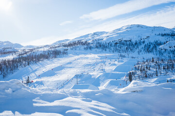 View over ski resort with slopes, chair lifts and majestic snowy mountains during winter day. Hemsedal ski center in Norway.